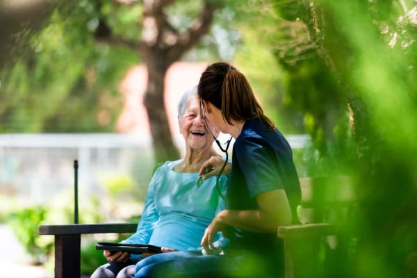 A senior woman and her nurse sitting on a bench at Ramsey Village Continuing Care in Des Moines, Iowa