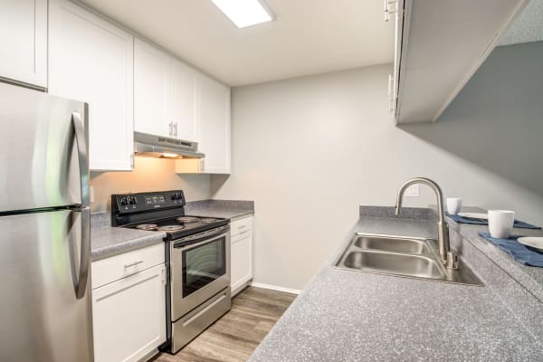 white kitchen cabinetry renovation with stainless steel appliances at Kendallwood Apartments in Whittier