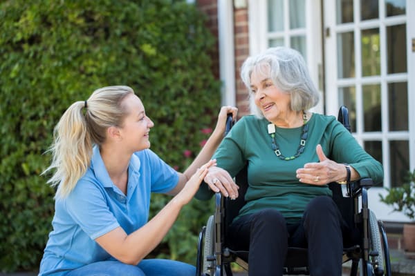 Staff helps resident in wheelchair at First & Main of Auburn Hills in Auburn Hills, Michigan
