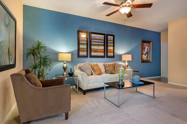 Model living room with plush carpeting and ceiling fan at Foundations at River Crest & Lions Head in Sugar Land, Texas