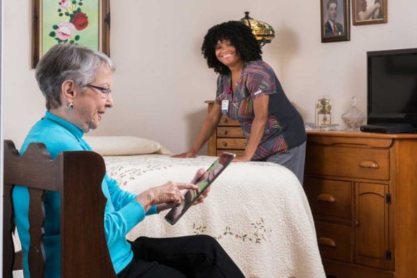 a woman on her tablet with a nurse in the room at Wesley Place on Honeysuckle in Dothan, Alabama 