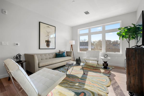Modern decor in the living area with large bay windows providing incredible city views from an apartment home at Anden in Weymouth, Massachusetts