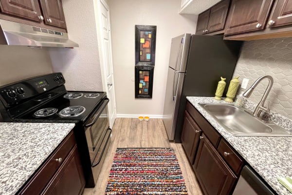 Kitchen view including a stove and refrigerator in our apartments at The Abbey at Montgomery Park in Conroe, Texas