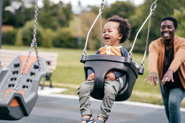 Resident pushing their child on a swing at the playground at Hunters Crossing in Newark, Delaware