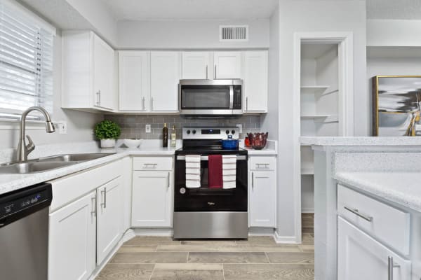 Fully equipped kitchen with white cabinetry and tiled backsplash at The Carling on Frankford in Carrollton, Texas