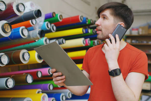Man on phone checking rolls of colored paper