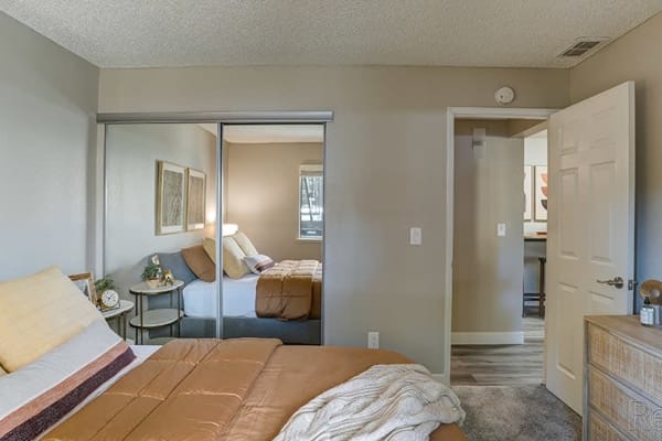 Spacious bedroom decorated in calm, neutral tones at Austin Commons Apartments in Hayward, California
