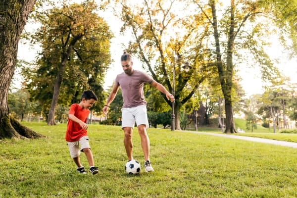Father and his kid playing soccer in park near Eaton Village in Chico, California