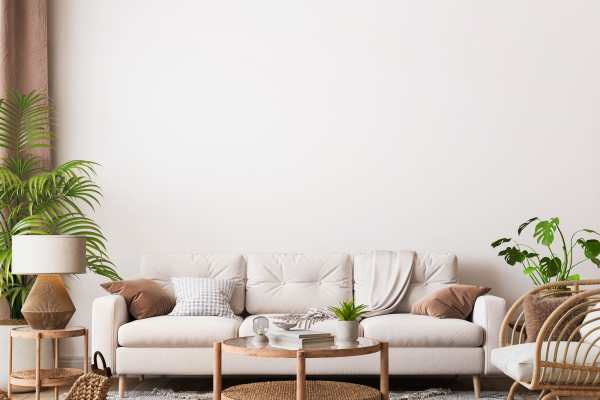 Stylish living room featuring a light-colored sofa adorned with cushions, a round coffee table, and decorative plants, complemented by natural light and a warm ambiance, against a neutral wall at Aqua Terra in Greenbrae, California