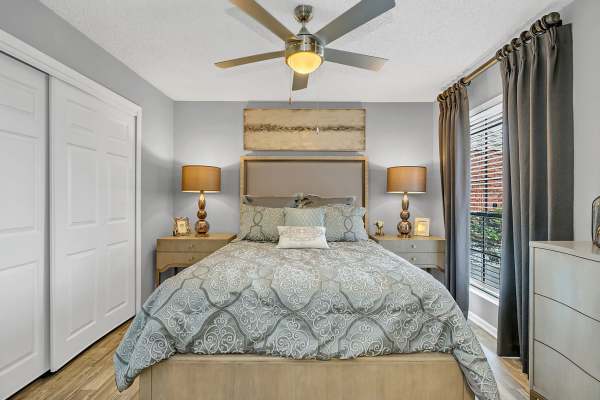 Comfortable bedroom with a bed, ceiling fan, two side lamps and a large window at Rosemont Windermere in Orlando, Florida