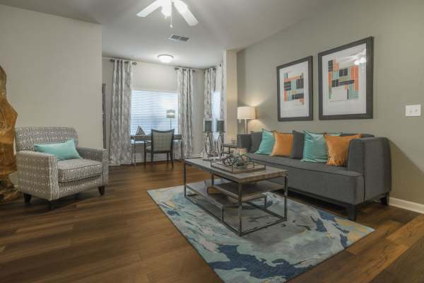 Spacious living room with vinyl flooring, comfortable couch, coffee table, ceiling fan and a large window at The Haven At West Melbourne in West Melbourne, Florida