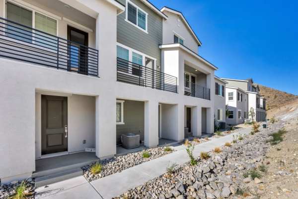 Contemporary apartment building with a minimalist design, showcasing glass balconies and a vibrant entrance at Prosper 83 in Sparks, Nevada
