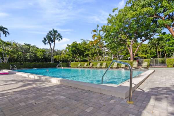 The community swimming pool with lounge seating beside it at Forest Place in North Miami, Florida