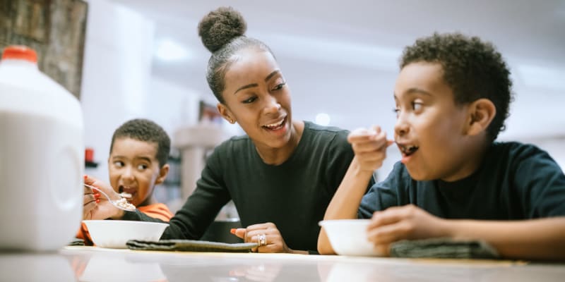 A smiling resident eating cereal with her kids at Bruns Park in Port Hueneme, California