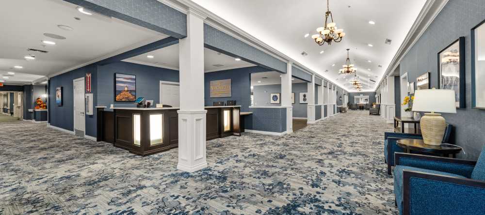Wide hallway with blue carpeting, seating areas, and decorative lighting