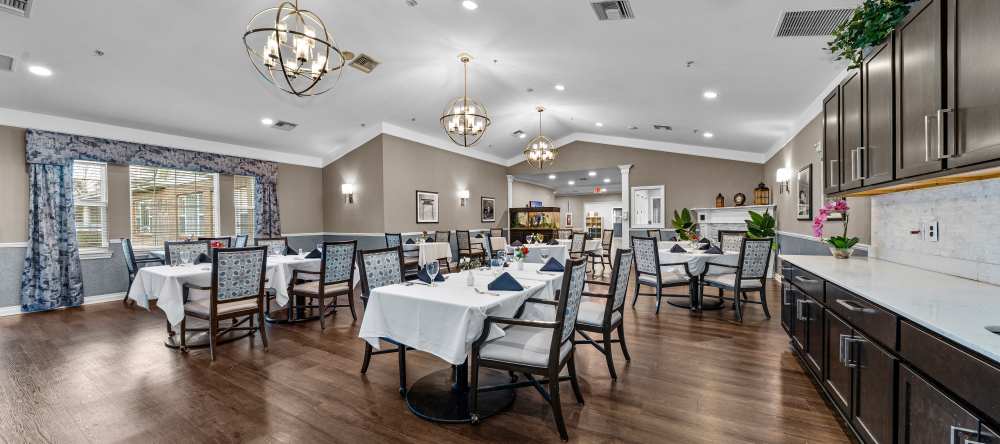 Spacious dining hall with set tables, chandeliers, and dark wood cabinetry