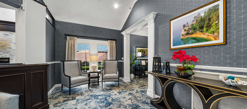Stylish lobby seating area with patterned carpet and framed artwork at Waltonwood Cherry Hill in Canton