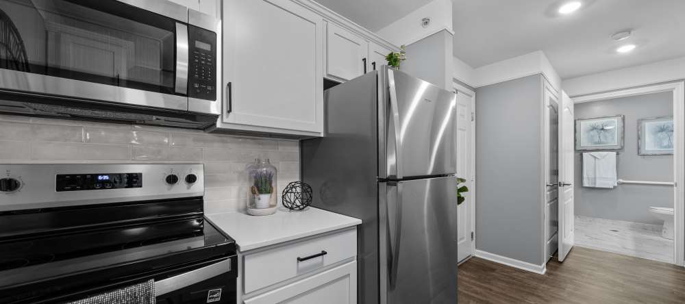 Modern kitchen with stainless appliances, white cabinets, and wood floors at Waltonwood Cherry Hill in Canton