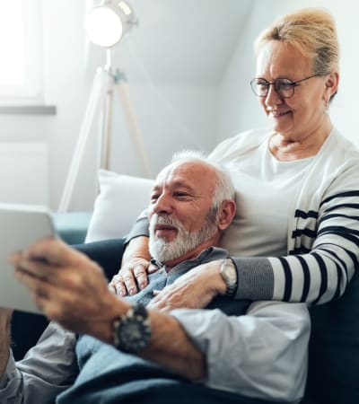 Couple on the couch watching a show on their tablet at Fairview Senior Apartments in Rising Sun, Maryland