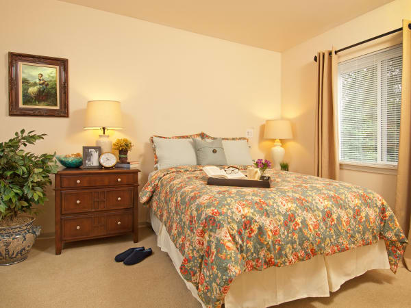 A resident bedroom with a nightstand at Patriots Glen in Bellevue, Washington. 