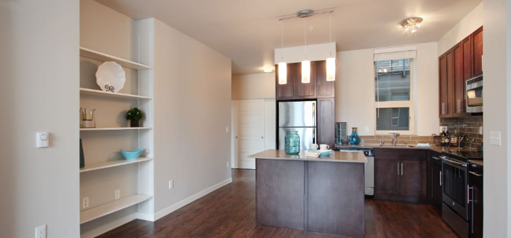Dining area with built-in shelving and gourmet kitchen with a large island and pendant lighting at Motif Apartments in Lynnwood, Washington