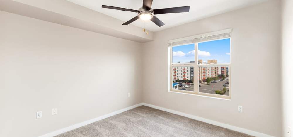 Well-lit bedroom with plush carpet, ceiling fan and large windows at Lumen in Everett, Washington, 