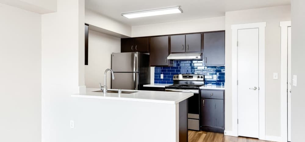Spacious island kitchen, dishwasher, and wood cabinetry at Lumen in Everett, Washington 
