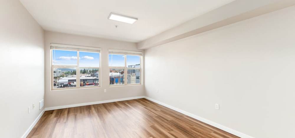 Spacious living room with large windows and wood-style flooring at Lumen in Everett, Washington, 