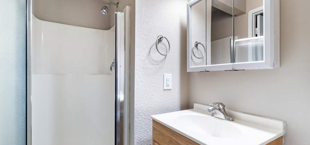 Modern bathroom with cabinets and shower stall at The Courtyard Apartment Homes in Mukilteo, Washington