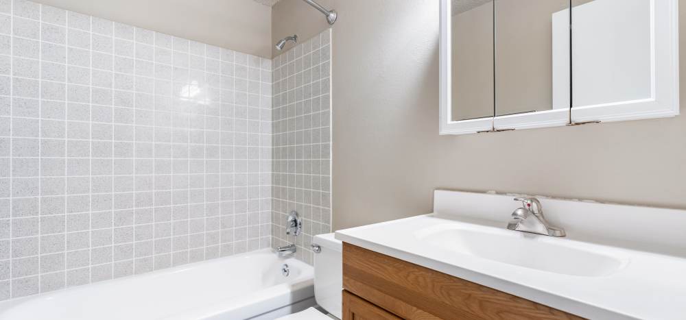 Bathroom with storage cabinets, tub and shower at The Courtyard Apartment Homes in Mukilteo, Washington