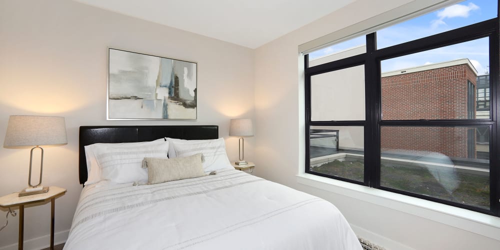 Furnished bedroom with a lovely view of the city at Madrona Apartments in Washington, District of Columbia