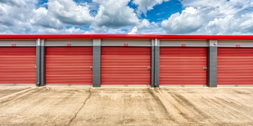 Row of outdoor storage units with bright orange doors at Devon Self Storage in Conroe, Texas