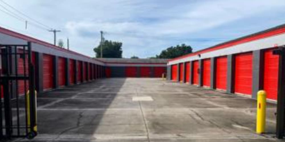 Wide driveway and bright red doors on secure outdoor storage units at Devon Self Storage in Okeechobee, Florida
