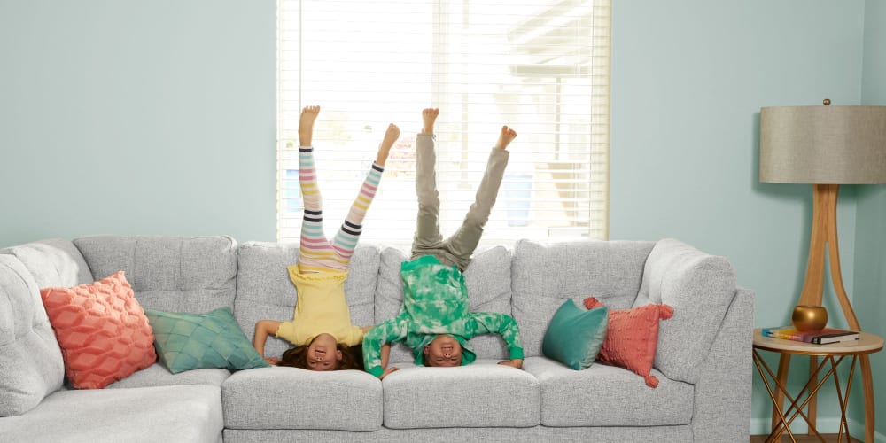 Two funny kids doing headstands on the couch at BB Living at Light Farms in Celina, Texas
