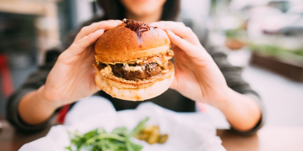 a resident eating a hamburger near Farmstead at Lia Lane in Santa Rosa, California