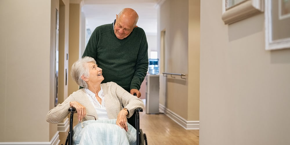 Resident couple rolling down a hallway at Vista Prairie at Ridgeway in New Ulm, Minnesota