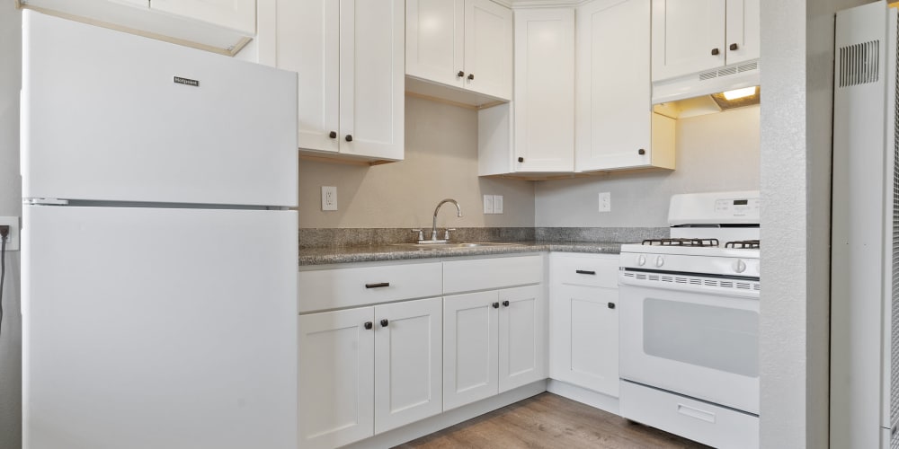 Fully equipped kitchen with white cabinetry and white appliances at Royal Gardens Apartments in Livermore, California