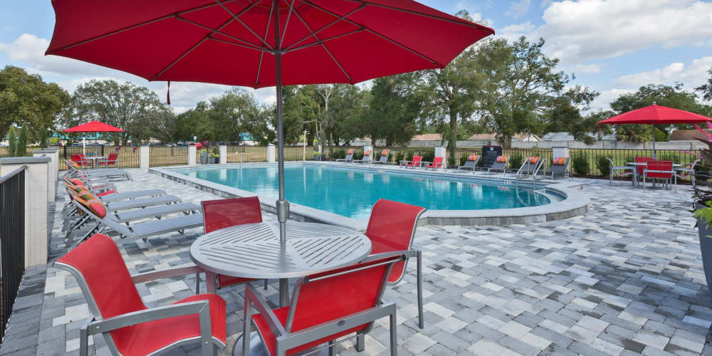 Seating with umbrella shade by the pool at Barrington Place at Winter Haven in Winter Haven, Florida