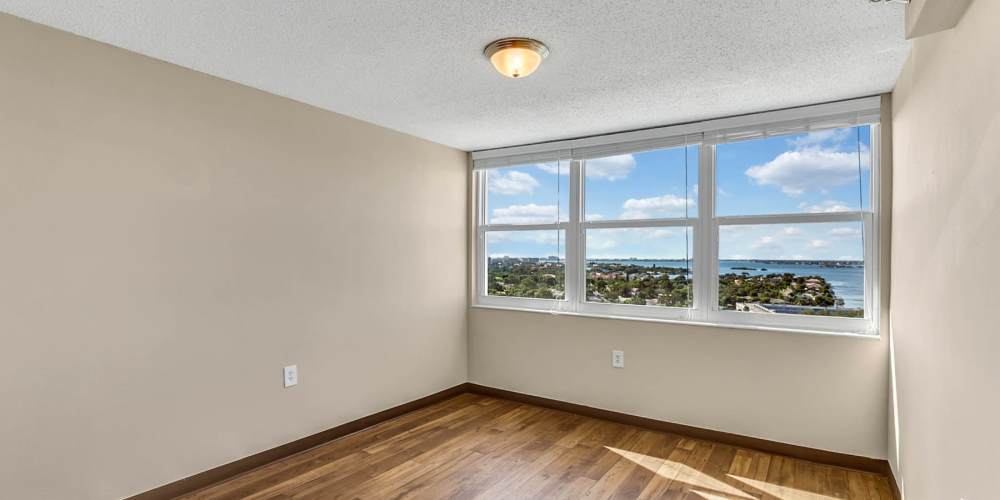 Apartment bedroom with hardwood floors and large windows at Bay Pointe Tower in South Pasadena, Florida