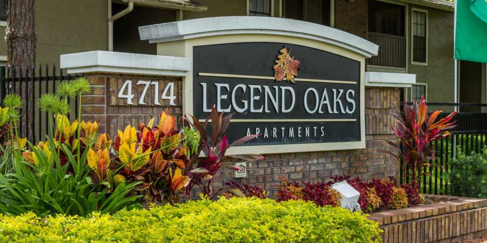 Exterior signage with beautiful gardens at Legend Oaks in Tampa, Florida