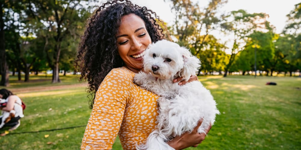 Resident and her dog hanging out in a park near Summerhill Terrace Apartments in San Leandro, California