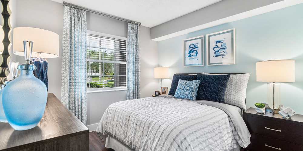Furnished apartment bedroom with queen-size bed and multiple lamps at Boynton Place Apartments in Boynton Beach, Florida
