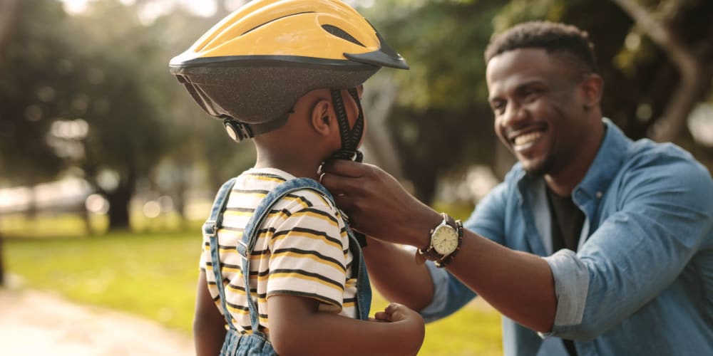 Dad helping his son put on a helmet near Mountain View Apartments in Concord, California