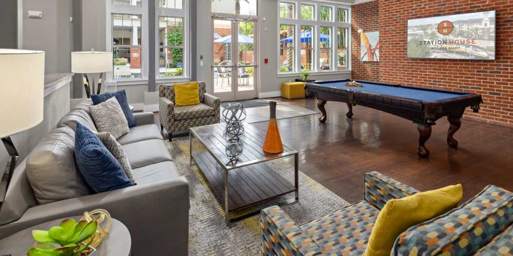 Community clubhouse with pool table and comfy seating at Station House at Lake Mary in Lake Mary, Florida