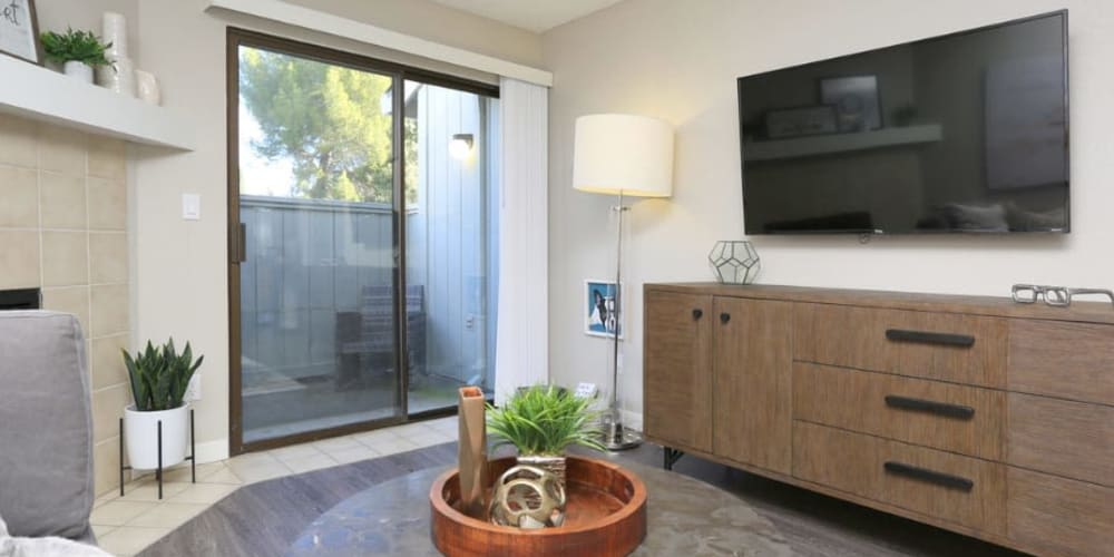 Draped bay windows and modern furnishings in a model home's living area at Ellington Apartments in Davis, California