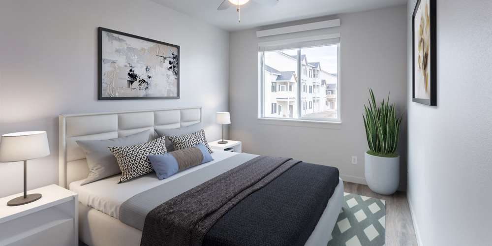 Apartment bedroom with a large bed and potted plant in the corner at 5 Points Apartments in Vancouver, Washington