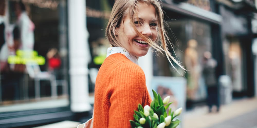 Woman smiling with flowers in the city near Josephine DTLA in Los Angeles, California