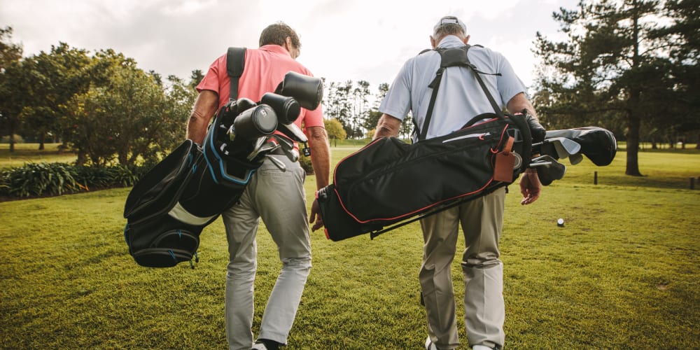 Two gentlemen carrying golf clubs on a course near The Station at Fleming Island in Fleming Island, Florida