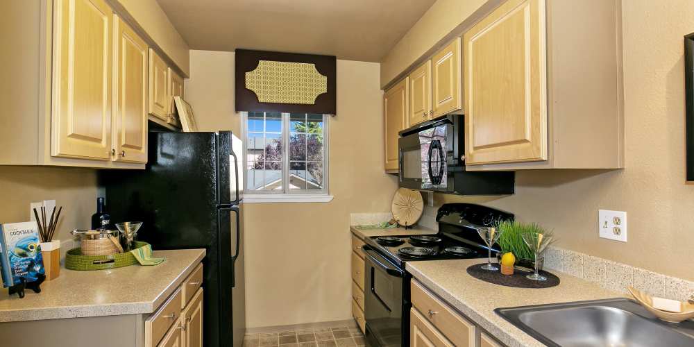 Apartment hallway kitchen with a dual basin stainless steel sink and black appliances at Collins Junction in Lynnwood, Washington