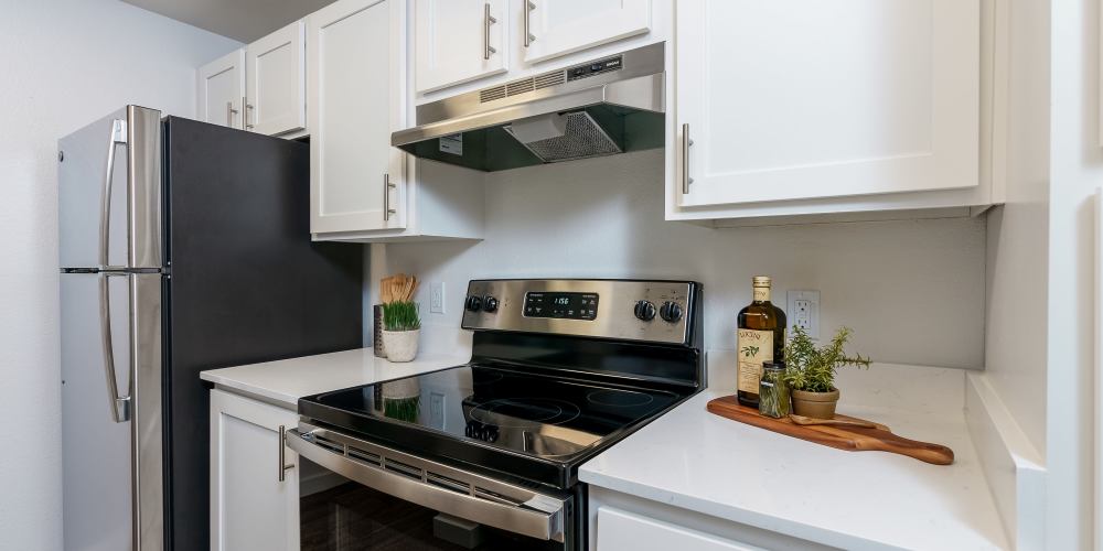 Apartment hallway kitchen with black and stainless steel appliances at Terra @ Monroe in Monroe, Washington